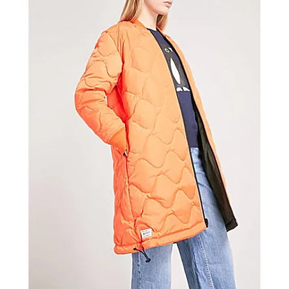 Woman wearing the CHOCOOLATE Reversible Two-Tone Shell Coat with the bright orange side facing outward. Styled with casual blue jeans, a navy top, and Vans, this version highlights the coat's versatile two-tone design, perfect for adding a pop of color.