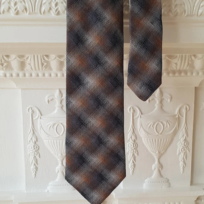 A view of the Duchamp Abstract Check Tie with its two ends separated, emphasizing the width and design of the wider blade alongside the slim tail. The silk material and abstract check pattern are clearly visible.