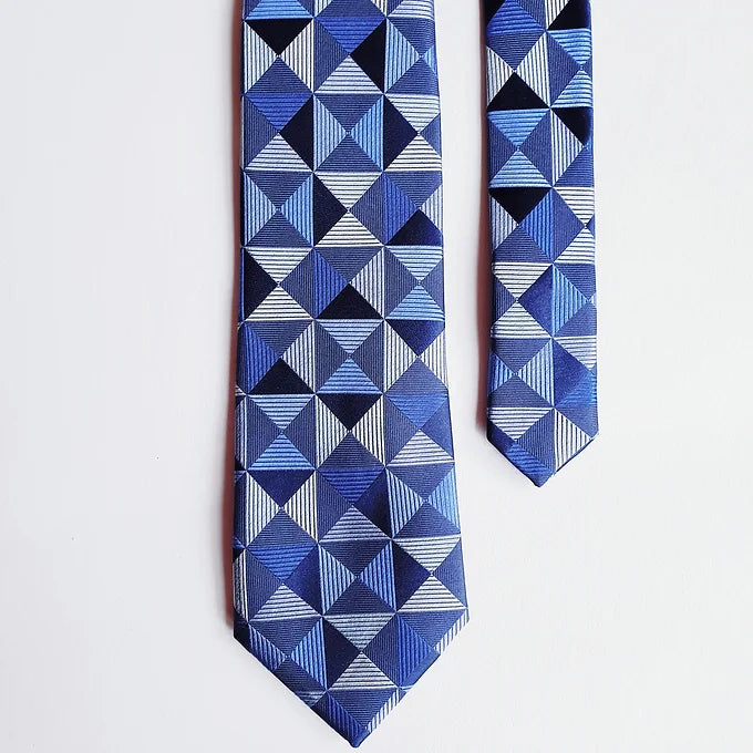 Duchamp London Blue Geometric Silk Tie laid flat against a slightly different background, with the tail positioned on the opposite side for a stylish arrangement. The geometric pattern on the pure silk fabric is clearly visible.