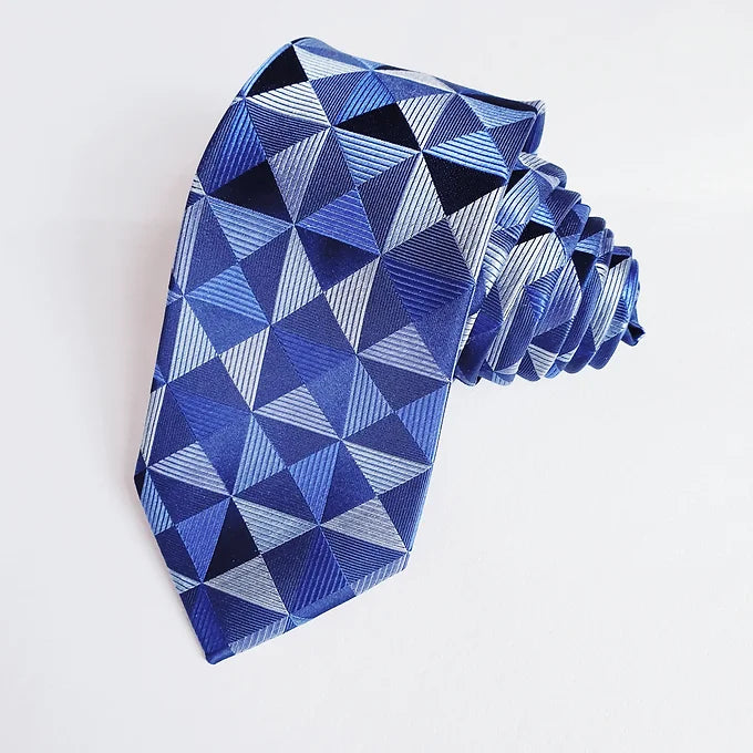 Duchamp London Blue Geometric Silk Tie rolled up neatly, showcasing the intricate geometric design on the wide blade tip of the luxurious blue silk fabric.